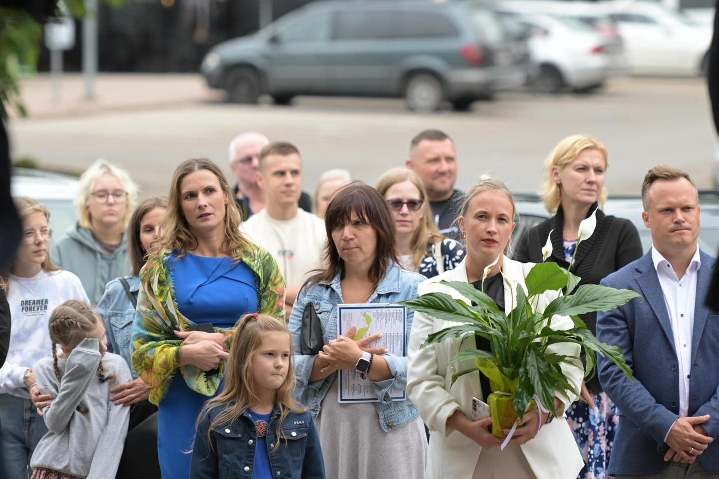 Cilvēki stāv ar ziediem rokās 23.08.2024.