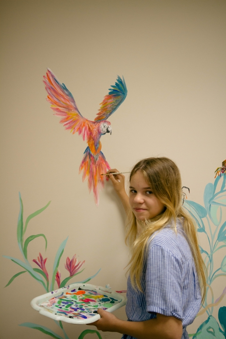 Ogres Mūzikas un mākslas skolas audzēknes apglezno sienu Ogres novada Sociālā dienesta telpās